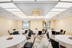 a room with white tables and chairs and windows at The Inn at Long Beach in Long Beach