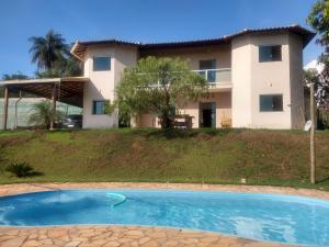 a villa with a swimming pool in front of a house at Sitio Lugar de Descanso em Lagoa Santa in Jaboticatubas