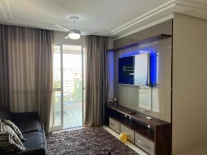 uma sala de estar com uma televisão de ecrã plano na parede em apartamento praia do morro - beira mar em Guarapari