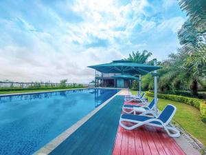 Prince Manor Resort في بنوم بنه: مسبح مع كراسي صالة ومظلة