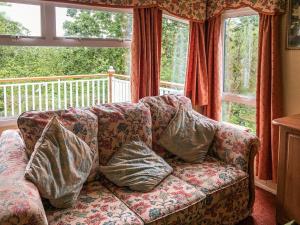 a couch with pillows sitting in front of a window at Siskin Lodge - Uk39664 in Lunga