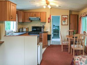 a kitchen with wooden cabinets and a table and a dining room at Siskin Lodge - Uk39664 in Lunga