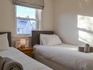 two beds in a room with a window at Derwent Cottage in Keswick