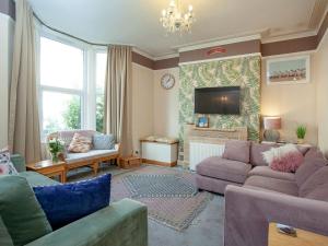 a living room with purple couches and a tv at Devon Beach Station in Paignton