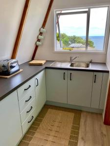 a kitchen with a sink and a window at Gull Cottage in Hahei