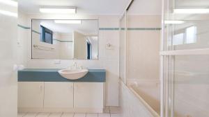 un bagno con un lavandino, uno specchio e una vasca di Seacrest Unit 1 Moffat Beach QLD a Caloundra