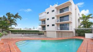 un edificio con piscina di fronte a un edificio di Seacrest Unit 1 Moffat Beach QLD a Caloundra