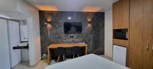 Habitación con mesa y TV en la pared. en ARARAS Apart Hotel - CTC, en Caldas Novas