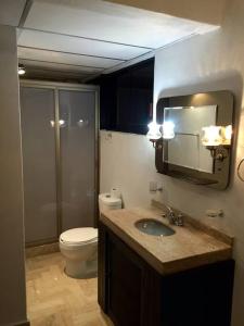 a bathroom with a toilet and a sink and a mirror at Departamento Familiar en Acapulco con Hermosa Vista! in Acapulco