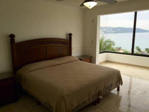 a bedroom with a bed and a large window at Departamento Familiar en Acapulco con Hermosa Vista! in Acapulco