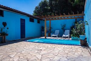 uma piscina com duas cadeiras e uma casa azul em Casa c ótima localização piscina e WiFi, Cuiabá em Cuiabá