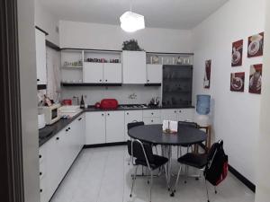 - une cuisine avec des placards blancs, une table et des chaises dans l'établissement Room in Apartment - very bright well kept apartment, à Marsaskala
