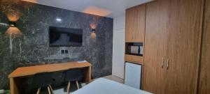 1 dormitorio con escritorio y TV en la pared en ARARAS Apart Hotel - CTC, en Caldas Novas