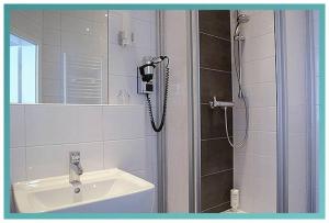 a bathroom with a shower, sink, and mirror at Gästehaus Küste in Nordenham