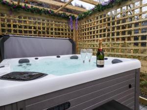 a hot tub with a bottle of wine and glasses at Lovies Place - Crossgate Luxury Glamping in Penrith +11 photos