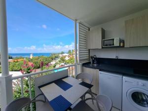 uma cozinha com uma varanda com uma mesa e cadeiras em Appartement vue mer, résidence avec piscine à Tartane em La Trinité
