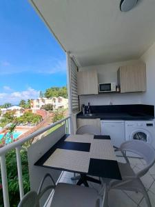 a balcony with a table and chairs and a kitchen at Appartement vue mer, résidence avec piscine à Tartane in La Trinité