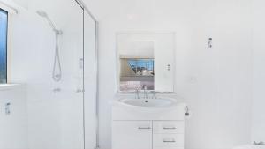un bagno bianco con lavandino e doccia di Wickham Point Unit 5 Kings Beach QLD a Caloundra