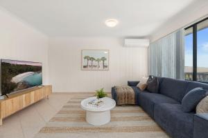 a living room with a blue couch and a tv at A Pets Paradise by Experience Jervis Bay in Vincentia