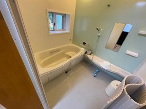 uma casa de banho com uma banheira, um WC e um lavatório. em ゲストハウス餓鬼大将 em Omachi