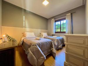 1 dormitorio con 2 camas y ventana en Apartamento Dom Políbio 2 dorm by Achei Gramado, en Gramado
