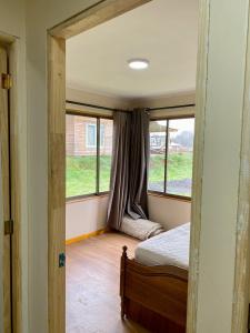 a bedroom with a bed and two windows at Cabaña Loncoche / Villarrica in Loncoche