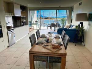 eine Küche und ein Wohnzimmer mit einem Tisch und Stühlen in der Unterkunft Blue on Blue Apartment 933 in Nelly Bay