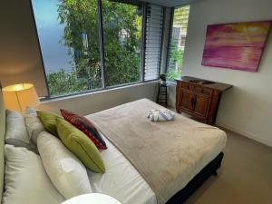 ein Schlafzimmer mit einem Bett und zwei großen Fenstern in der Unterkunft Blue on Blue Apartment 933 in Nelly Bay