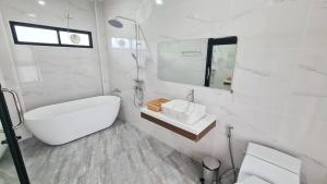 a white bathroom with a tub and a sink at Phorpun Resort 