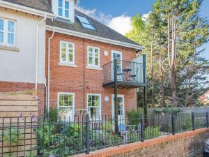 a brick house with a balcony and a fence at Forest Acorn in Brockenhurst