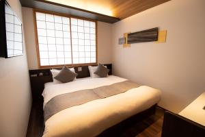 a bedroom with a bed and two windows at Stay SAKURA Kyoto SUZAKU OJI in Kyoto