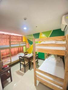 a room with three bunk beds and a table at BOPEMPC Safari Hostel in Tagbilaran City