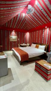 a bedroom with a large bed and red walls at Bidiya Desert Camp in Aflāj