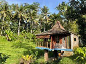 a small house in a field with palm trees at Tepi Sawah Lodge & Retreat in Jatiluwih