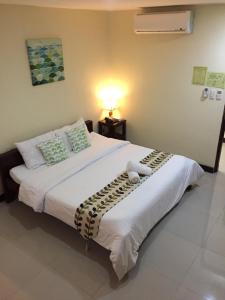 ein Schlafzimmer mit einem großen Bett mit weißer Bettwäsche und Kissen in der Unterkunft BOPEMPC Safari Hostel in Tagbilaran