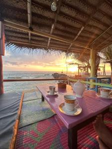 a table with cups and plates on it on the beach at Oynise Beach Cabin in Galle