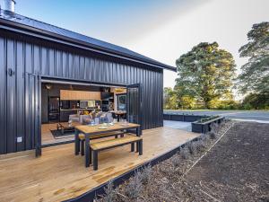 a house with a wooden deck with a table at Mangawhero River Chalet in Ohakune