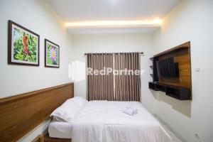 a small bedroom with a bed and a television at Balmoral House Mitra RedDoorz near Ambarukmo Plaza Mall Yogyakarta in Yogyakarta