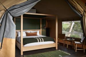 梅頓的住宿－Metung Hot Springs，一间帐篷内带天蓬床的卧室
