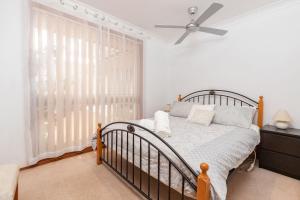a bedroom with a bed and a ceiling fan at Waterfront Haven with your own private jetty in Forster