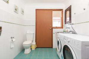 a bathroom with a toilet and a washer and dryer at Waterfront Haven with your own private jetty in Forster