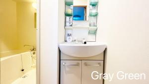 een badkamer met een witte wastafel en een spiegel bij Maison Milano Nakatsu Apartment in Osaka +102 foto's