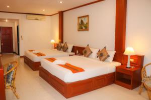 a bedroom with two beds and a table and chairs at Andaman Seaside Resort - SHA Extra Plus in Bang Tao Beach