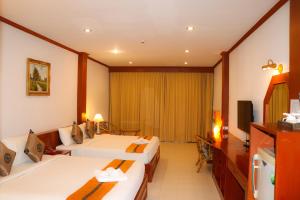 a hotel room with two beds and a television at Andaman Seaside Resort - SHA Extra Plus in Bang Tao Beach