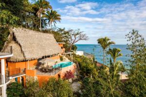 an orange house with a swimming pool next to the ocean at Casa Flourish, Yelapa in Yelapa