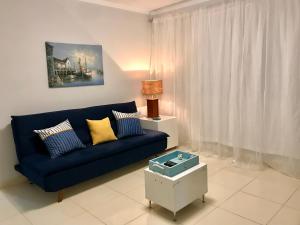 sala de estar con sofá azul y mesa en 3 QUARTOS,10 min a pé Praia Grande, GARAGEM 3 carros, Churrasqueira, Wi-Fi e Cozinha Completa, en Arraial do Cabo
