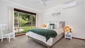 a bedroom with a bed and a large window at Banksia in West Cambewarra