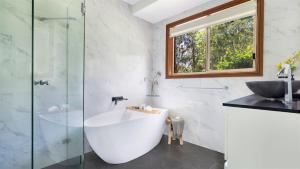 a bathroom with a bath tub and a sink at Banksia in West Cambewarra