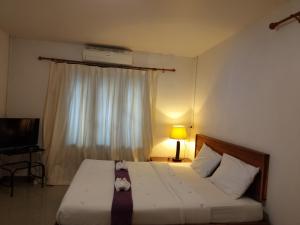 1 dormitorio con 1 cama, TV y ventana en ภูริรักษ์ โฮมสเตย์, en Ban Pha Saeng Lang