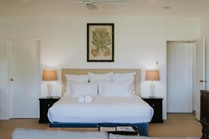 a bedroom with a white bed with two tables and two lamps at Corunna Station Country House in Belford